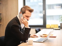 man having a phone call in front of a laptop