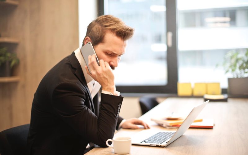 man having a phone call in front of a laptop