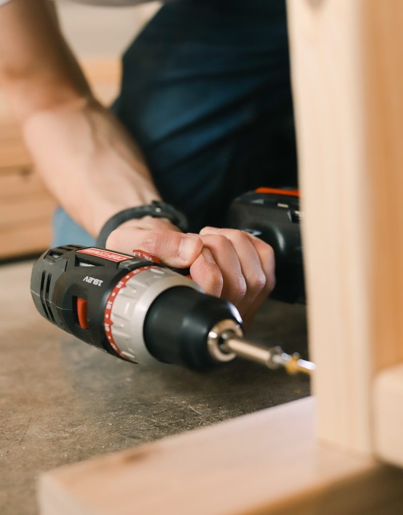 person holding black and red cordless hand drill