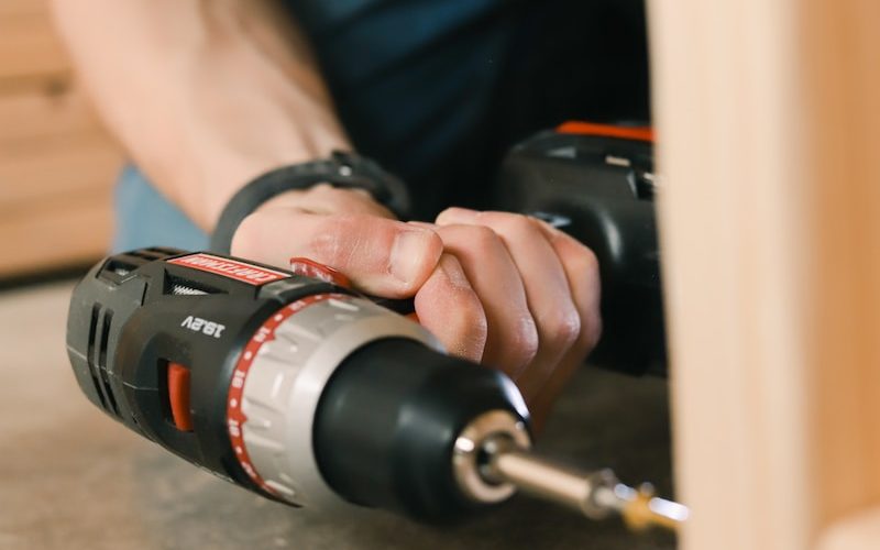 person holding black and red cordless hand drill