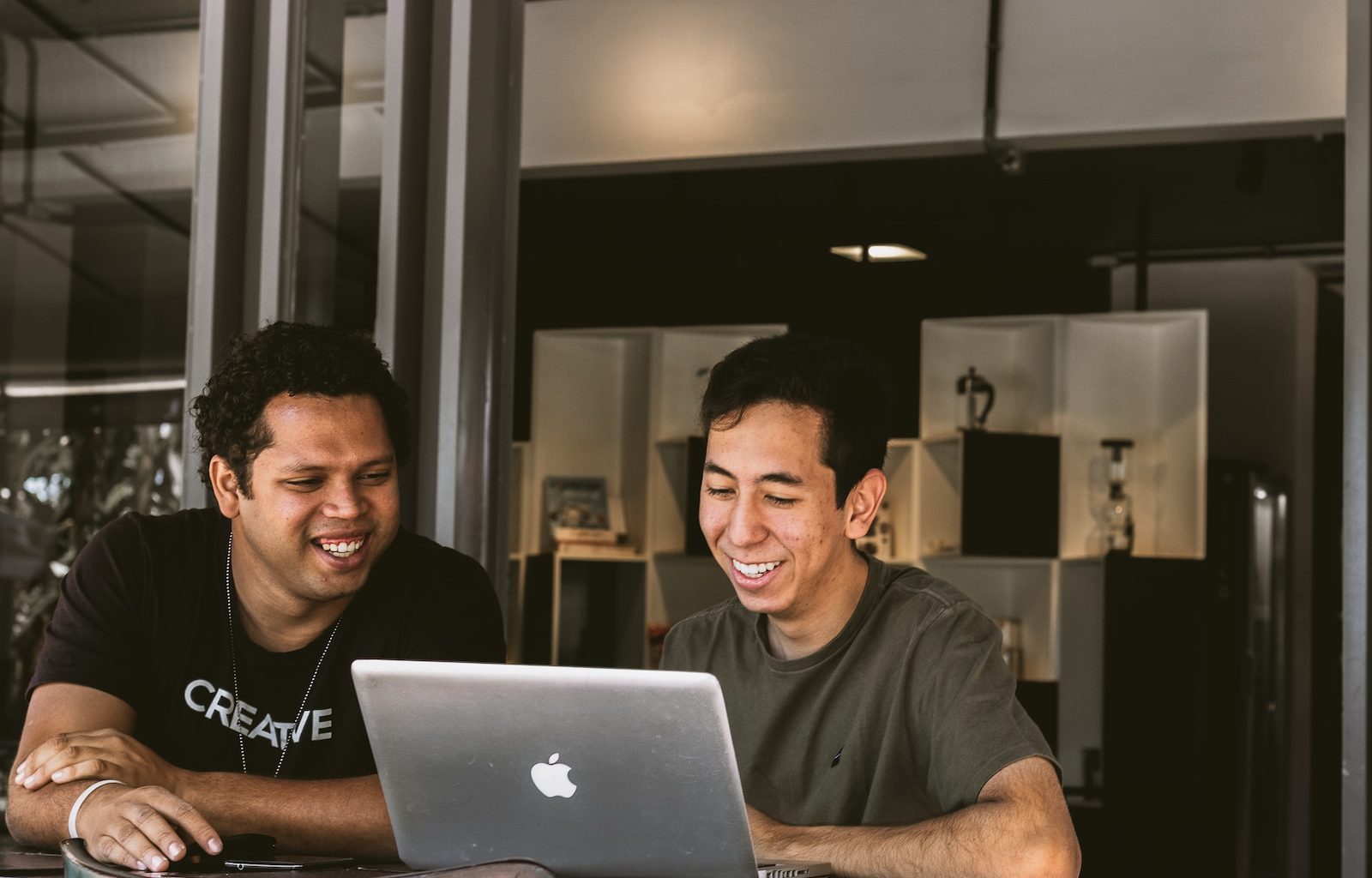 two smiling men looking at MacBook