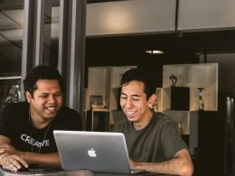 two smiling men looking at MacBook