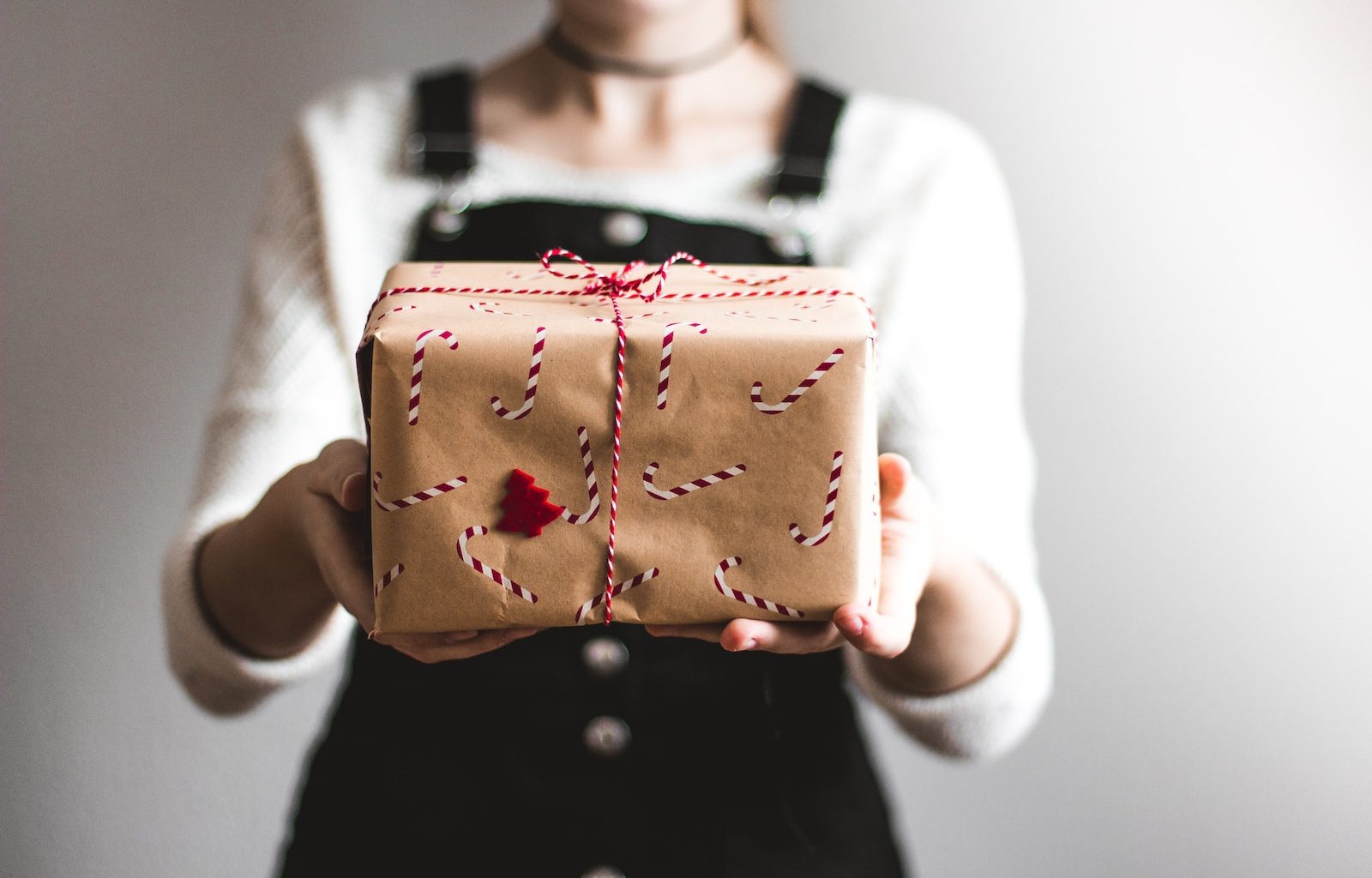 tilt-shift lens photography of woman holding candy cane-print gift box in a well-lit room