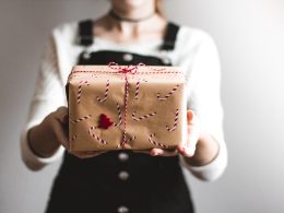 tilt-shift lens photography of woman holding candy cane-print gift box in a well-lit room