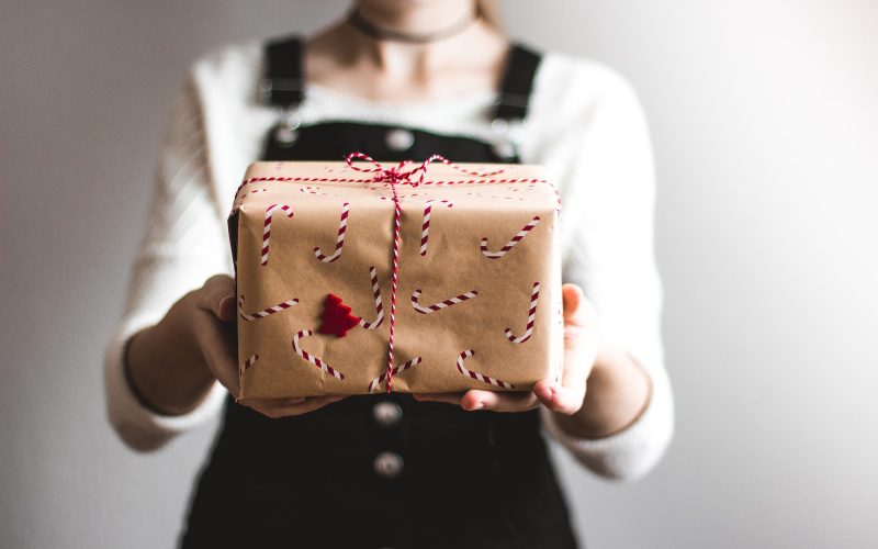 tilt-shift lens photography of woman holding candy cane-print gift box in a well-lit room