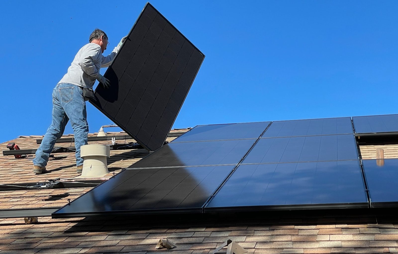 man in white dress shirt and blue denim jeans sitting on white and black solar panel