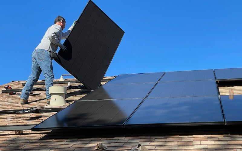 man in white dress shirt and blue denim jeans sitting on white and black solar panel