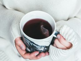 person holding white and black cup with teabag inside