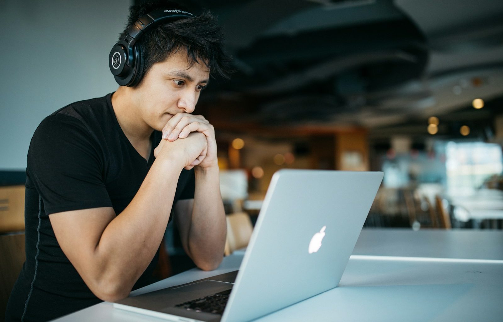 man wearing headphones while sitting on chair in front of MacBook