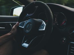 person holding on black steering wheel inside car