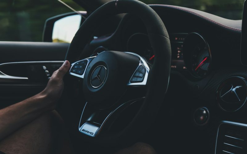 person holding on black steering wheel inside car