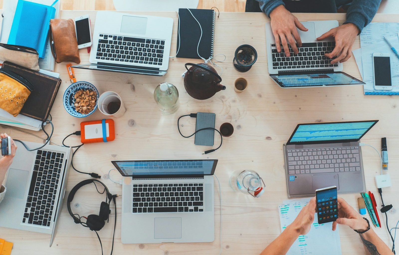 people sitting down near table with assorted laptop computers