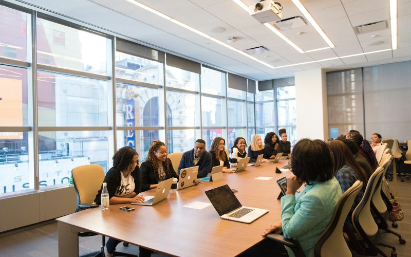 group of people sitting beside rectangular wooden table with laptops