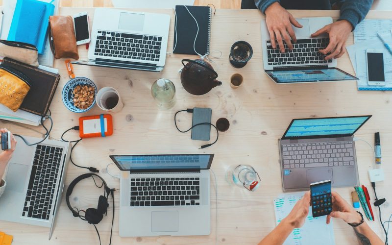 people sitting down near table with assorted laptop computers