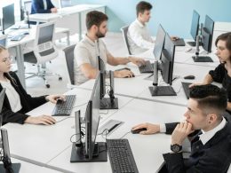 a group of people sitting at a table with computers