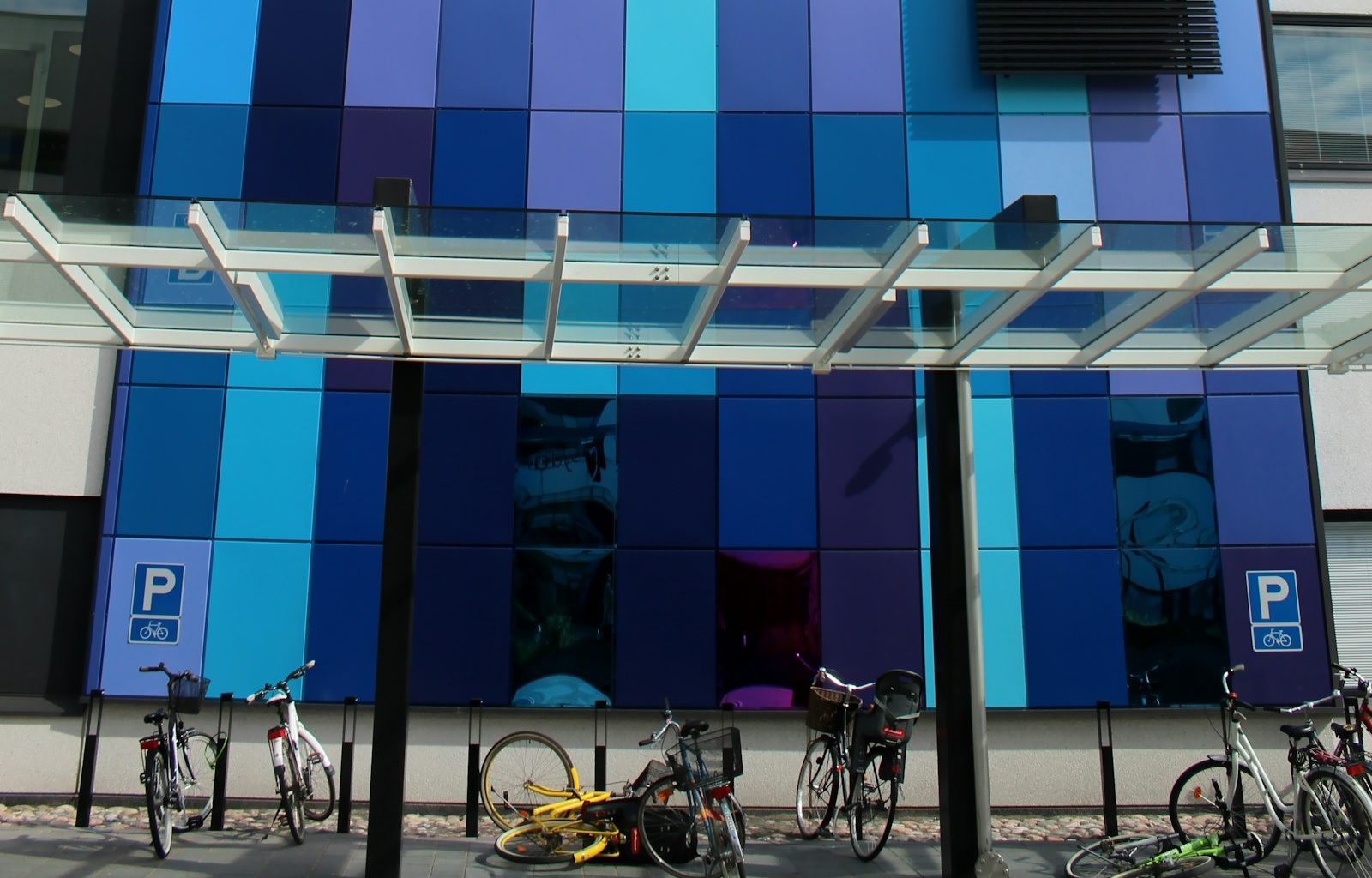 white and black city bikes parked beside blue and white building during daytime