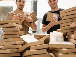 a couple of men standing next to a pile of boxes