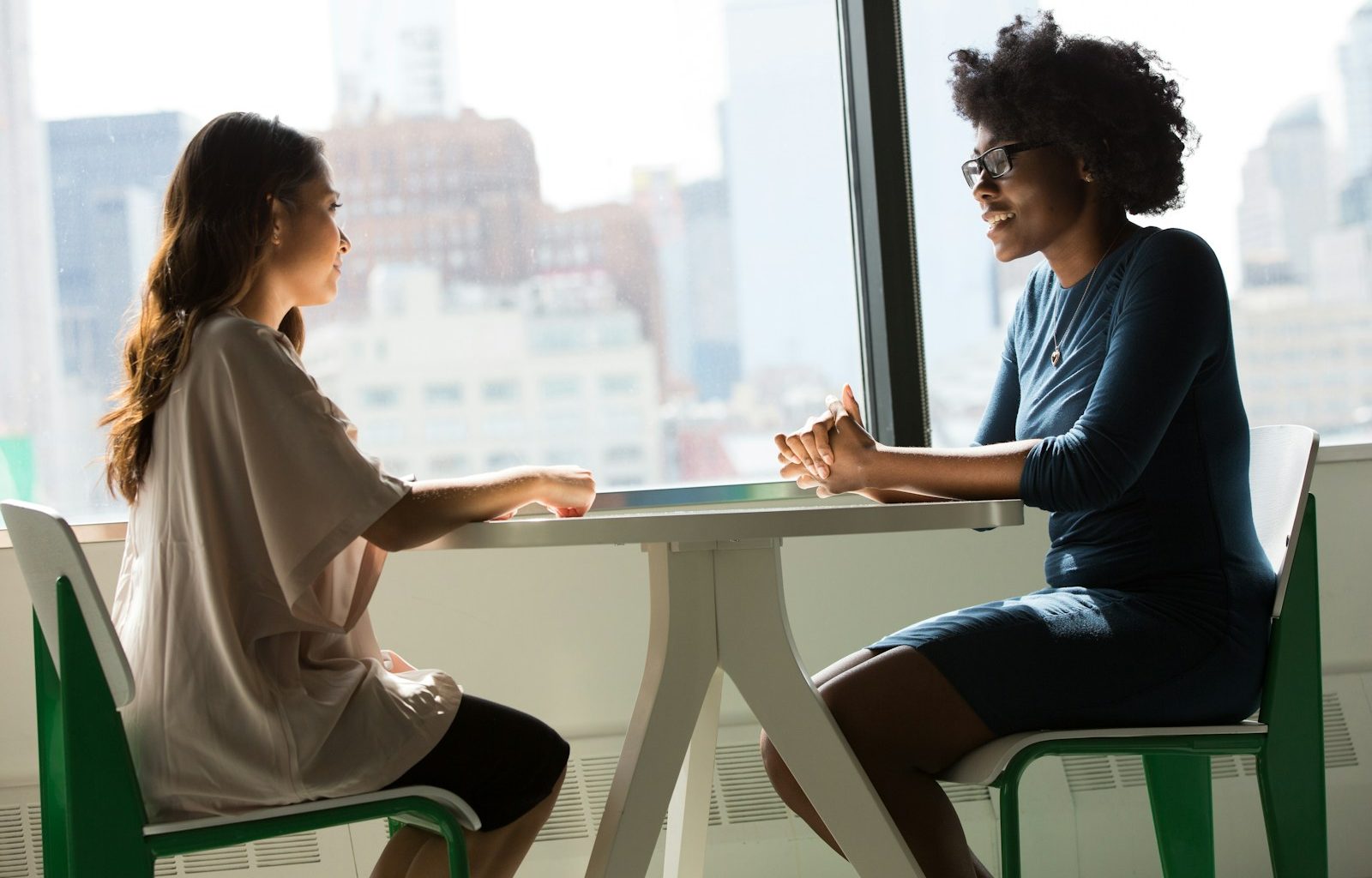two women sitting beside table and talking