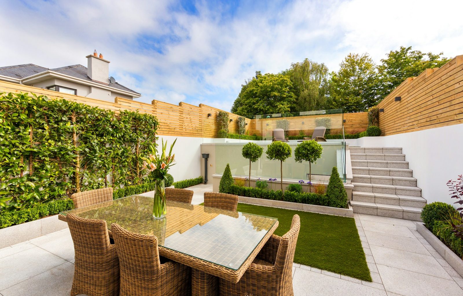 a patio with a table and chairs next to a fence