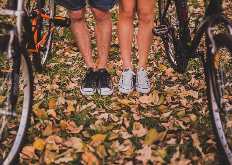 Gesloten houten compostbak in een tuin met herfstbladeren eromheen